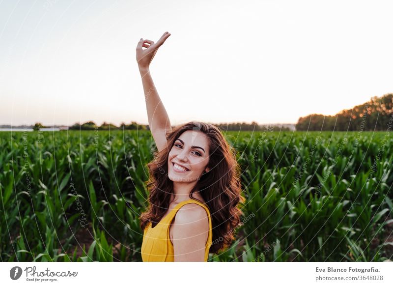 portrait of young beautiful woman wearing a yellow dress standing in a green corn field. Summertime and lifestyle 1 V sign beauty carefree casual caucasian