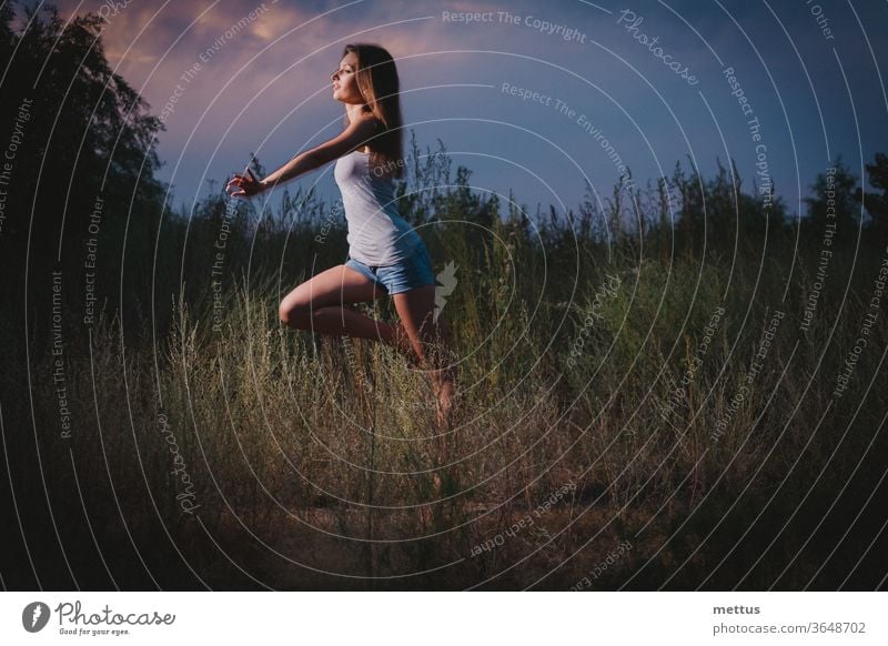 Slender lady is running or jumping in a tall grass in the night time girl jumping ecstatic ballet joyful lady young woman female happy freedom active silhouette