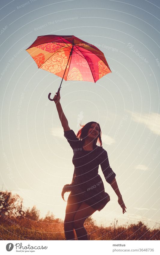 Jolly lady dancing happily with red umbrella in the sunset light in the fields. female freedom happy dress emotion classic person image sky background weather