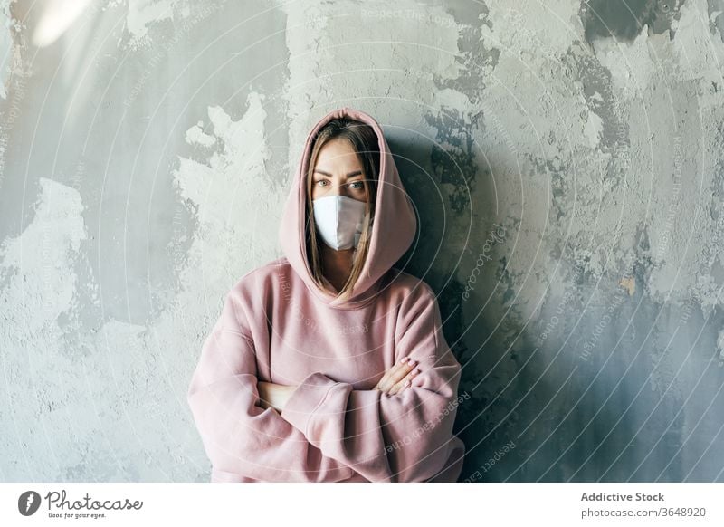 Woman in sterile mask standing near wall during quarantine period woman self isolation discontent coronavirus at home concrete domestic social distancing casual