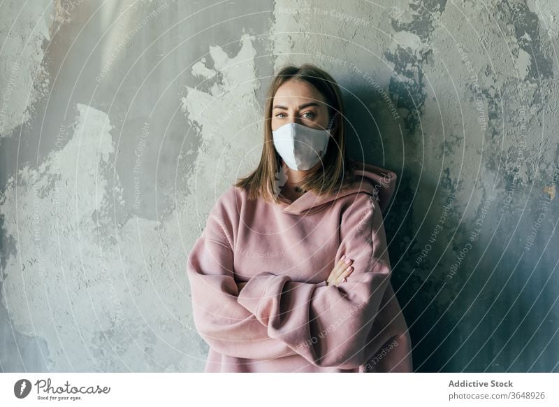 Woman in sterile mask standing near wall during quarantine period woman self isolation discontent coronavirus at home concrete domestic social distancing casual