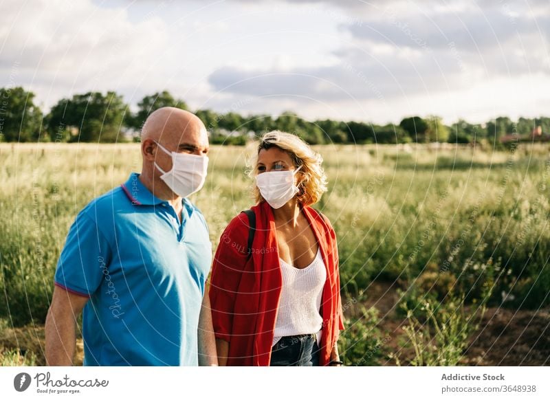 Couple in respirators walking in countryside area couple funny coronavirus casual mask protect relationship cute covid 19 epidemic outbreak affection summer