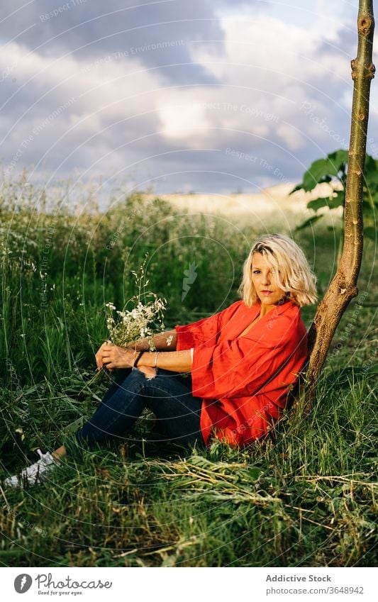 Relaxed woman resting on grassy field countryside trunk nature peaceful rural harmony idyllic daytime relax ground tranquil serene tree quiet flora casual