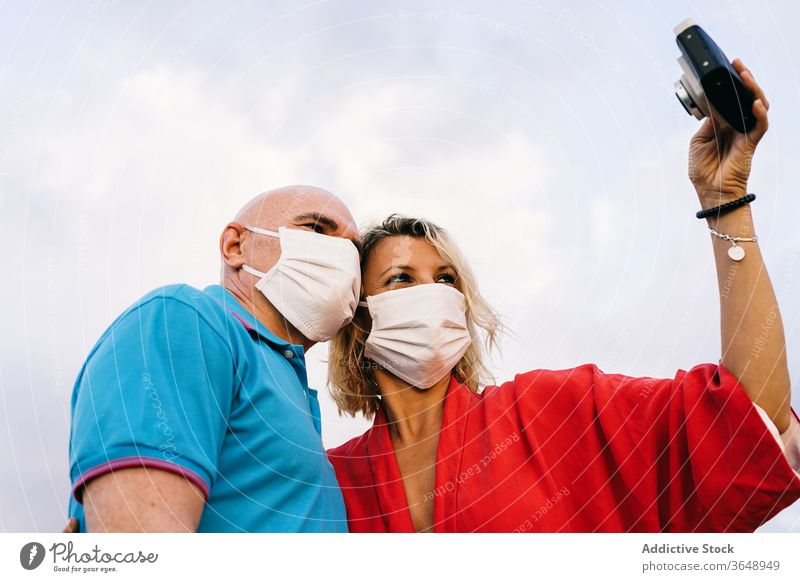 Happy couple in respirators taking selfie on smartphone mask adorable coronavirus summer content mobile phone using evening device nature woman funny