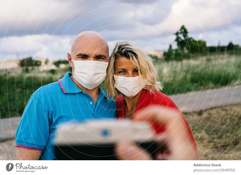 Happy couple in respirators taking selfie on smartphone mask adorable coronavirus summer content mobile phone using evening device nature woman funny