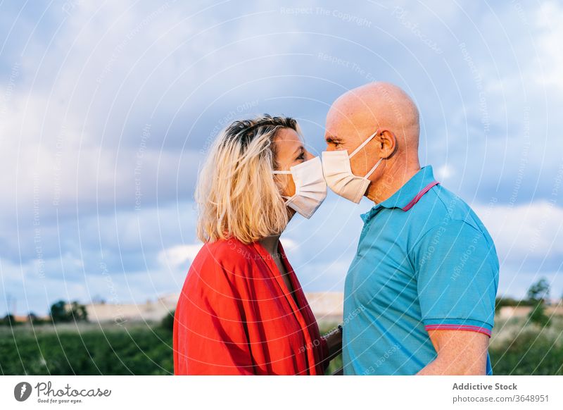 Romantic couple kissing through face masks in countryside summer romantic content covid 19 relationship love evening affection carefree nature summertime