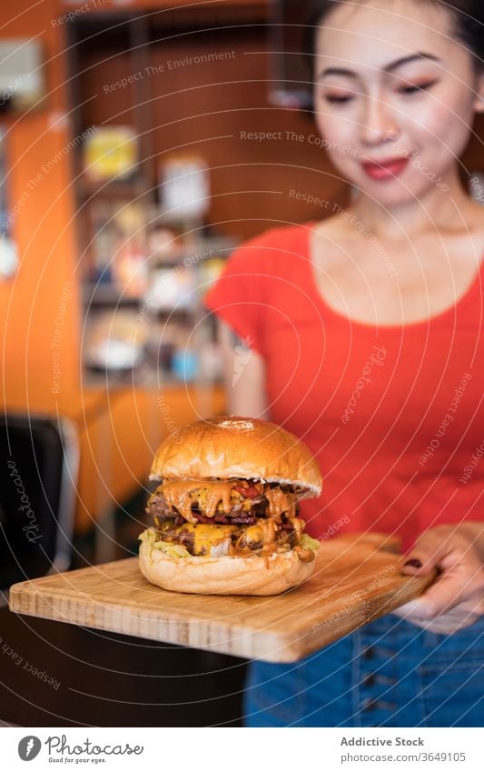 Crop Asian waitress serving burger in cafe serve woman cater delicious fast food tasty service female ethnic asian wooden meal happy table cafeteria hospitality