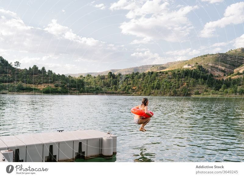Girl jumping into lake with inflatable ring rubber girl pond bikini summer vacation having fun teenage moment water happy recreation relax holiday joy freedom