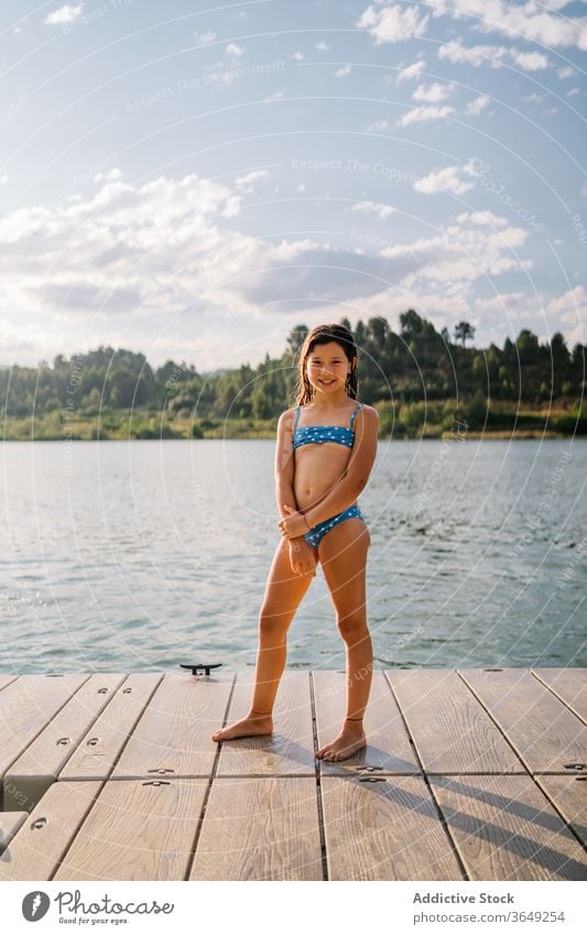 Playful girl standing in pier near lake pond summer holiday vacation enjoy child bikini water relax kid nature playful summertime sunny wooden daytime preteen