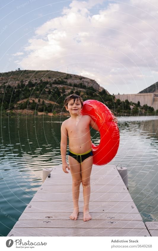 Boy with inflatable ring in lake boy rubber pond summer vacation cute smile having fun kid child water happy innocent cheerful childhood relax holiday joy