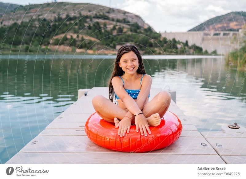 Carefree little girl on rubber ring on quay lake pier child relax holiday carefree smile inflatable preteen adorable water wooden summer vacation kid childhood