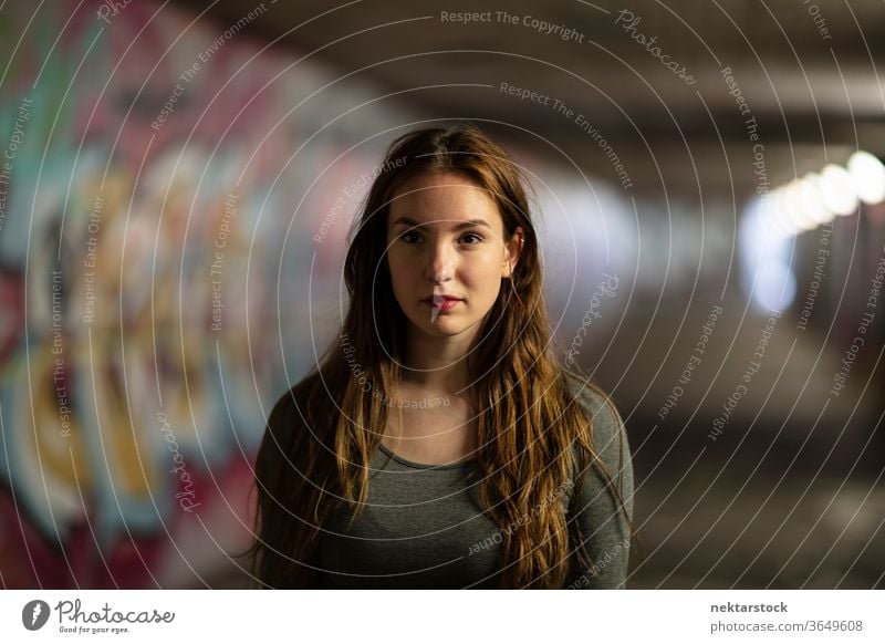Portrait of a Young Woman Standing in Tunnel portrait female one person girl close up confident young woman underpass selective focus headshot