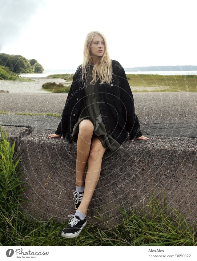 Backlit portrait of a young blonde woman on a concrete block by the sea Woman Young woman Blonde already Slim Long-haired windy Esthetic Summer Trip