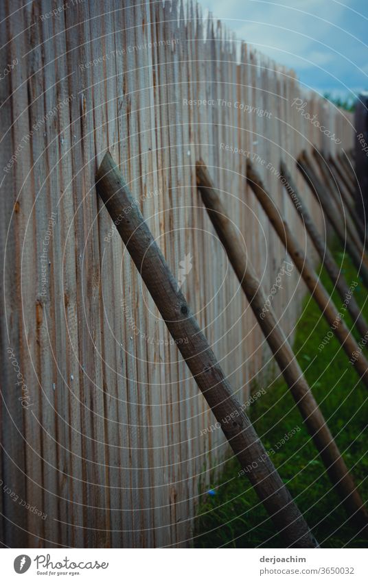 Intelligent solution - simply good and cheap. Wooden poles stand as support on a wooden fence. board wall Exterior shot Colour photo Deserted Nature Day Detail