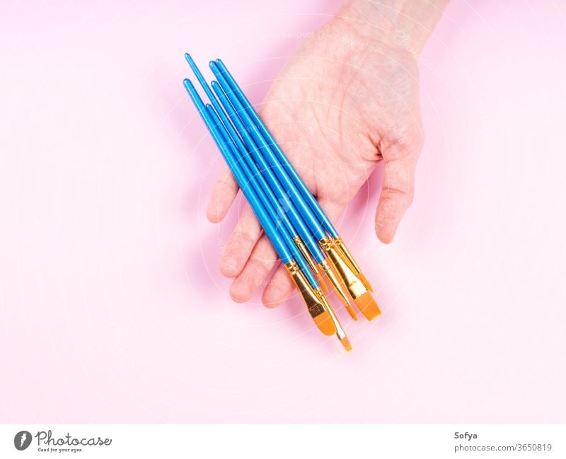Blue paintbrushes in woman's hand on pink art art supply artist flat lay bristle painting hold different background blue class craft design acrylic equipment