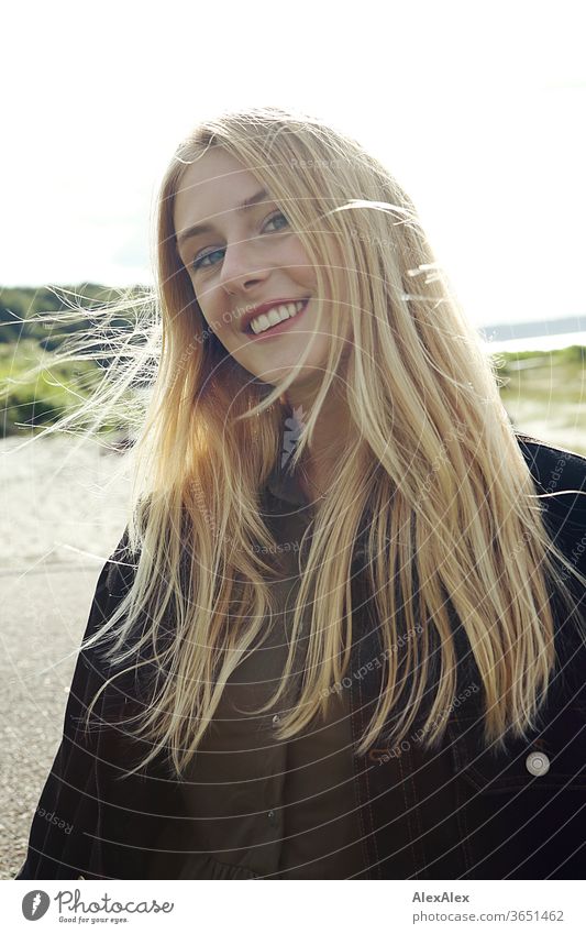Backlit portrait of a young, blond, smiling woman at the sea Woman Young woman Blonde already Slim Long-haired windy Esthetic Summer Trip Beautiful weather