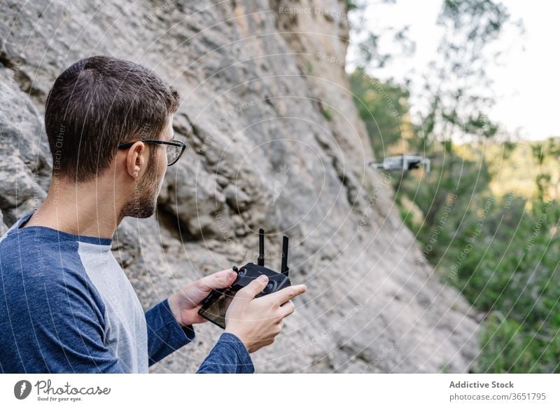 Focused man operating drone remotely control fly operate quadrocopter controller equipment unmanned flight male landscape mountain record video innovation