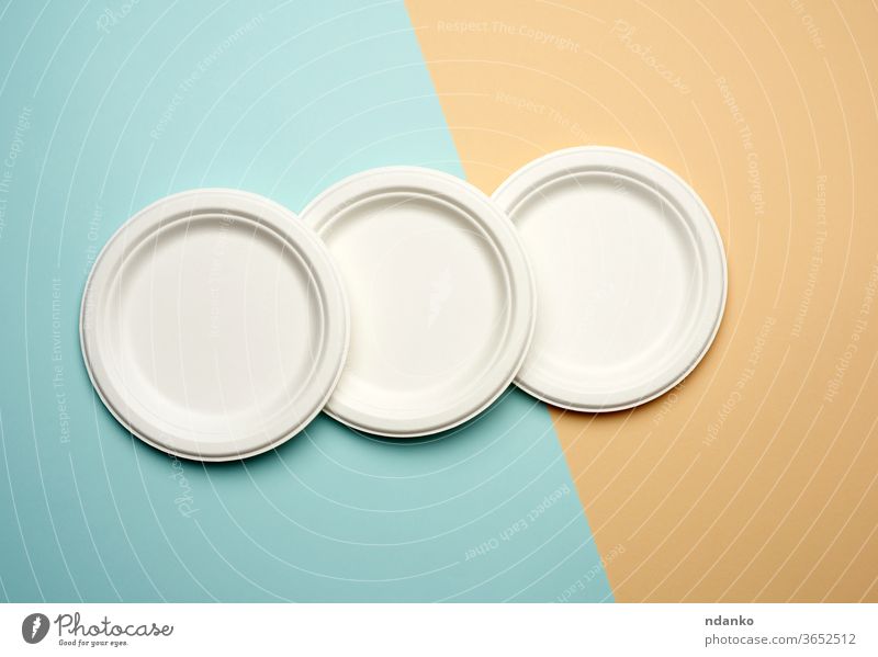 stack of white paper disposable plates on a beige-blue background, top view picnic recycle restaurant studio tableware template thick utensil zero waste
