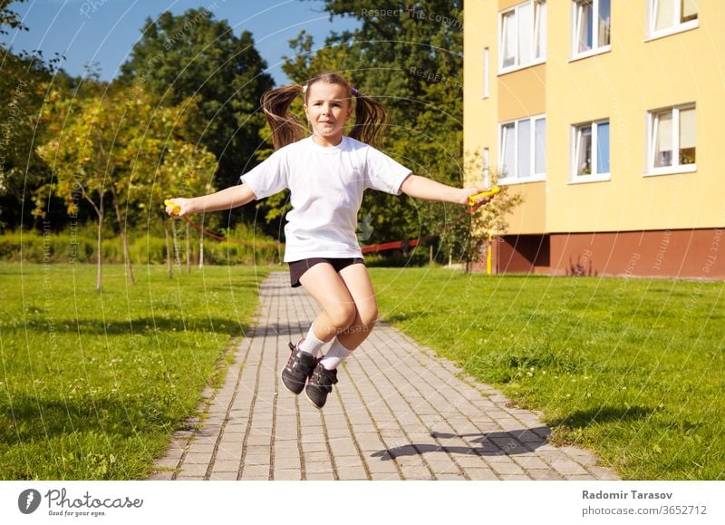 little girl jumping rope outside child cute beautiful white fun pretty cheerful lifestyle childhood play people caucasian kid joy action one beauty grass energy