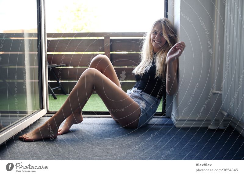 Full body portrait of a young, blond, barefoot woman sitting smiling in a balcony door Woman Young woman Blonde already Slim Long-haired Esthetic Summer