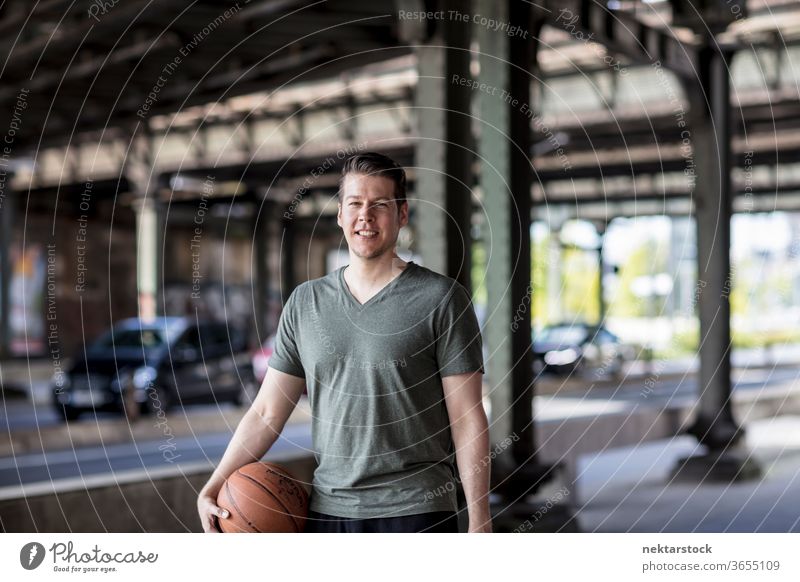 Man With Basketball Standing Under City Bridge adult basketball caucasian urban handsome model one person front facing looking at camera city bridge road