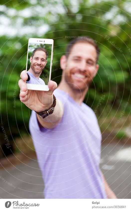 Casual guy in a park taking a photo person man mobile phone lifestyle young portrait selfie technology happy modern image male handsome people smartphone