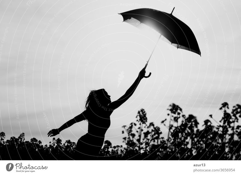 Unplugged free silhouette woman umbrella up to black white sky. Nature girl at windy rainy day has adventure wanderlust. Wonderful scene of imagination power and departure to new horizons in youth