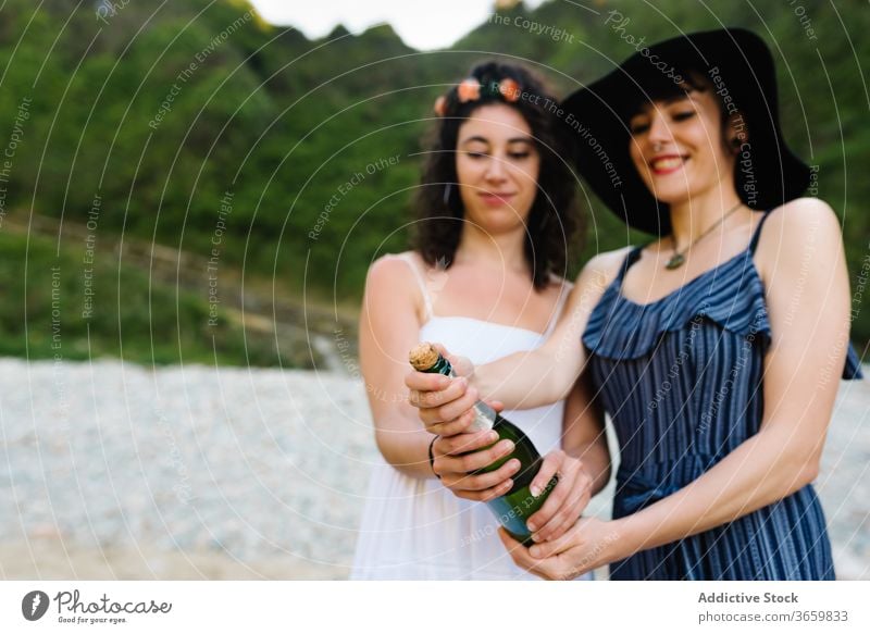 Gay couple opening bottle of champagne lesbian beach celebrate alcohol lgbt together women girlfriend weekend summer smile glass drink enjoy romantic