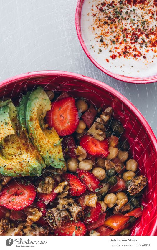 Crop woman with bowl of fresh delicious organic chickpea salad avocado strawberry walnut sauce healthy cutlery yummy ripe cream vegetarian diet meal female food