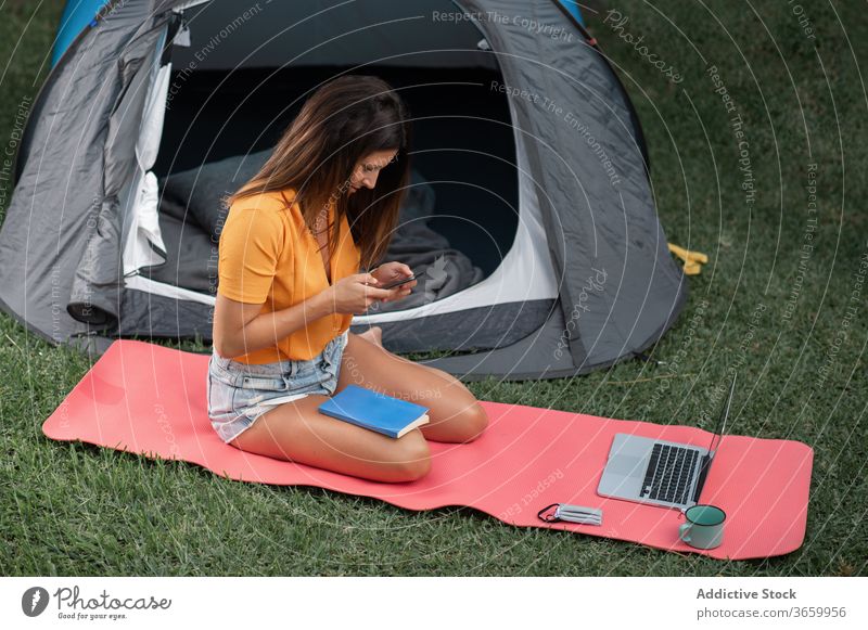 Young woman using gadgets during camping smartphone modern tent tourist positive nature young female casual laptop meadow device browsing rest vacation relax