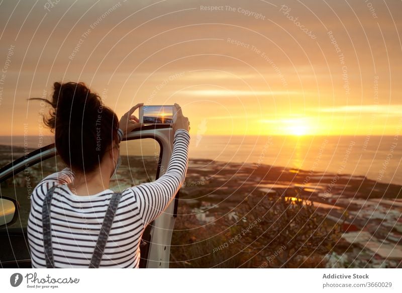 Anonymous tourist photographing picturesque seascape during sunset woman take photo smartphone amazing photography traveler ocean mobile female device gadget