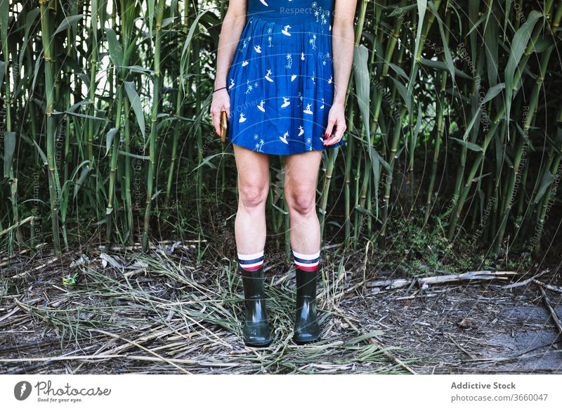 Crop woman in rubber boots in field countryside enjoy sun summer nature dress female freedom blue serene stand carefree grass rural tranquil idyllic peaceful