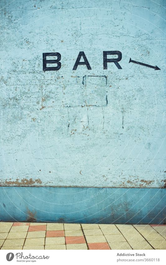 Concrete shabby wall with BAR title outdoors bar inscription scratch concrete tile floor arrow old indicator building rough blue color daylight cement