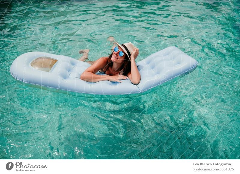 happy woman on inflatable having fun. Summer time swimming pool summer blue water relax hat sexy lifestyle sunglasses swimwear hot body tanning spa vibrant pink