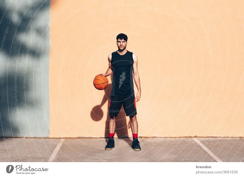 basketball player with the ball in front of a wall sport competition game athletic competitive playing exercise male exercising effort hobby match practicing