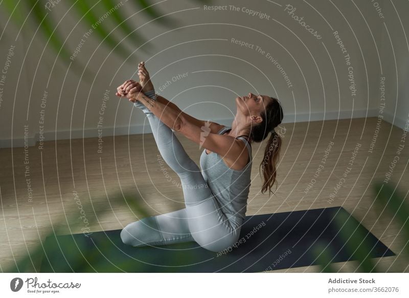 Focused woman performing Krauncasana stretching yoga pose practice studio heron flexible calm well being balance harmony wellness female fit sportswear healthy