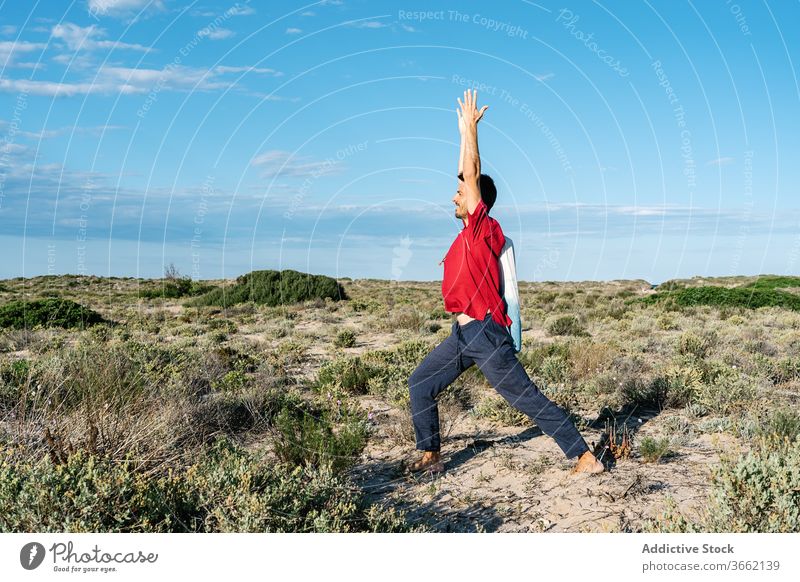 Male gymnast stretching legs and arms during yoga training on nature man asana sand terrain balance practice exercise relax harmony male casual muscular