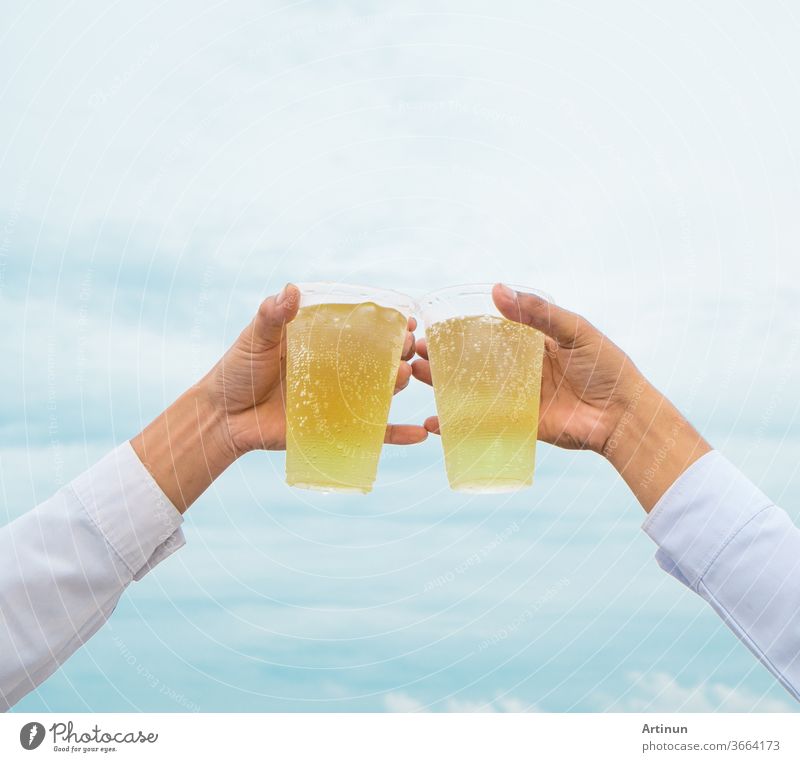 Celebrate a party, hold hands with plastic glasses and cheer on the success with a beautiful sky as background more adult Alcoholic drinks alcoholic already
