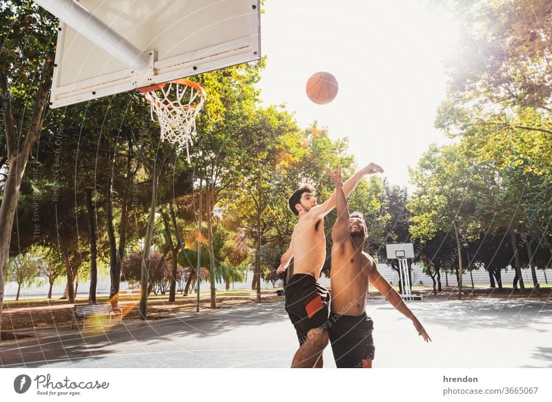 two young men play basketball outdoors sport competition game athletic competitive playing exercise male exercising effort hobby match practicing sporting
