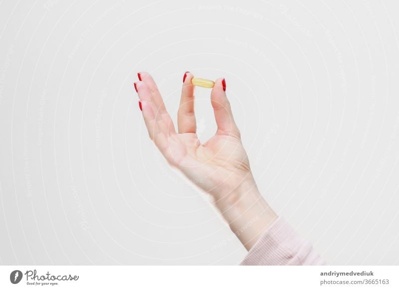 Hand holding capsule of Omega 3 on white background. Close up. High resolution product. Health care concept hand oil omega isolated fish healthy vitamin palm