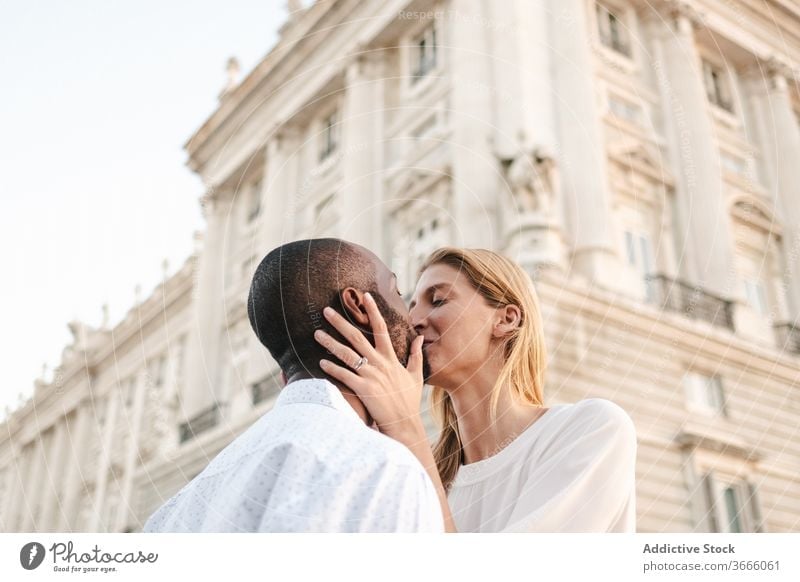 Positive multiethnic couple kissing on street bonding embrace positive candid love content madrid affection gentle casual lifestyle spain sunlight enjoy romance