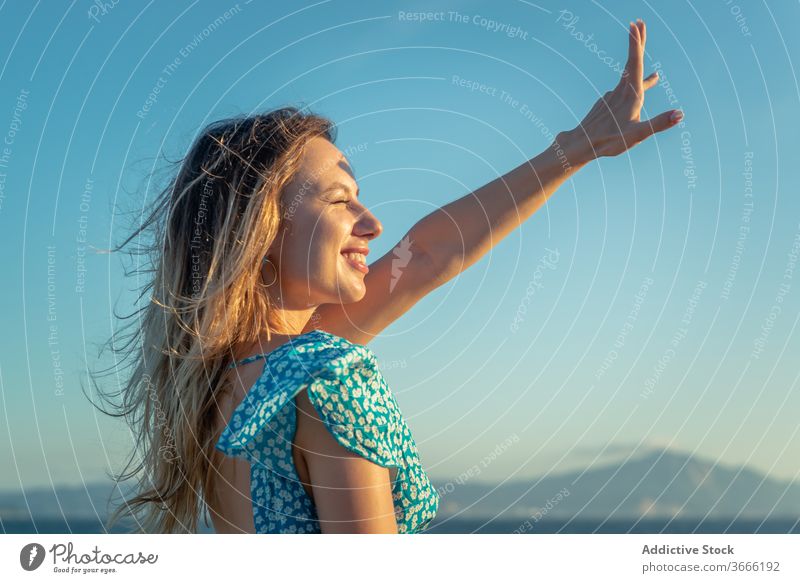 Smiling young female tourist recreating against calm ocean during sunset woman recreation seashore enjoy happy smile traveler summer vacation cheerful cloudless