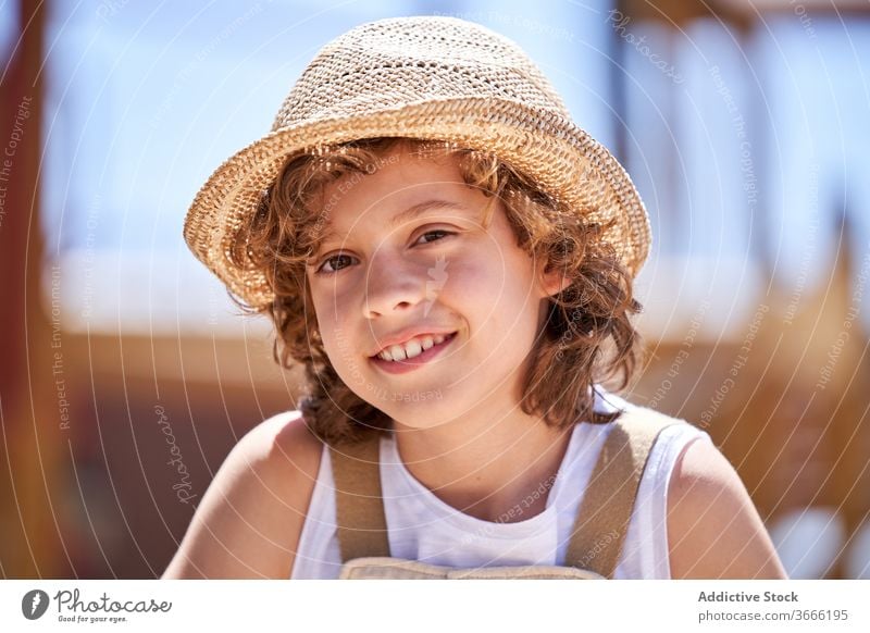 Cute boy in straw hat resting outdoors positive carefree relax toothy smile human face innocent child little kid cheerful summer childhood curly hair adorable