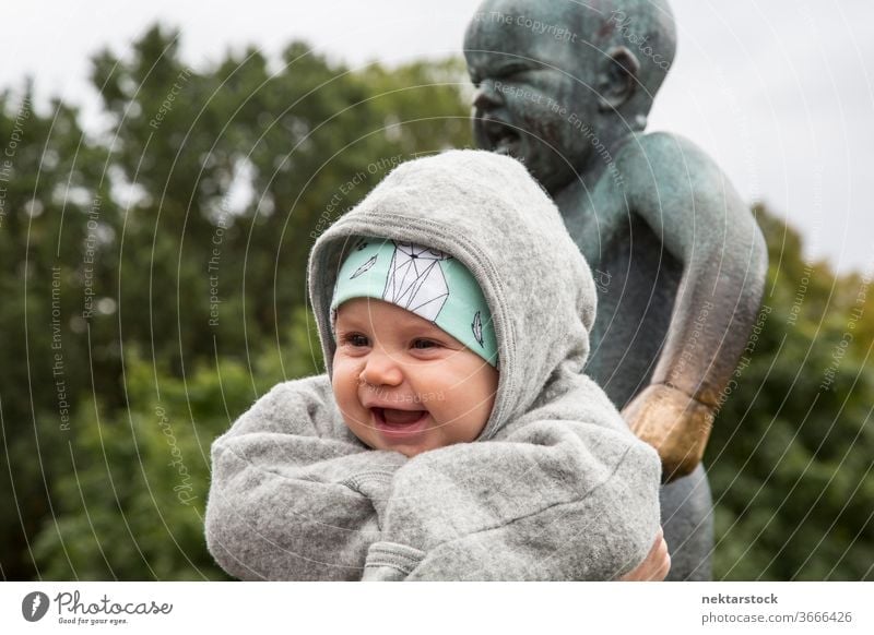 Laughing baby in front of statue with crying baby outside outdoors day toddler babies children one person happiness enjoyment laughing clothing casual top