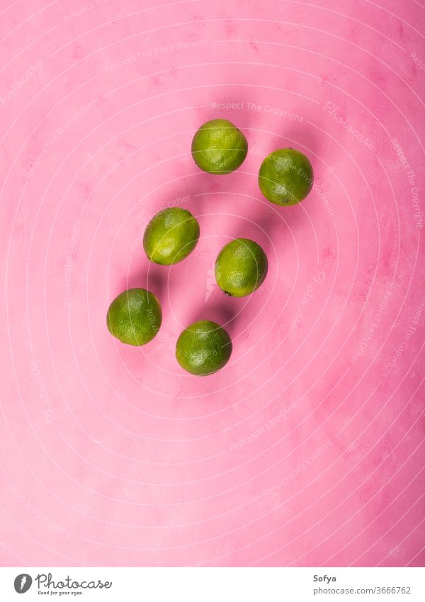 Fresh whole green limes on pink background flat lay vacation citrus barista colorful ingredient fruit cocktail drink party aperitif summer prepare