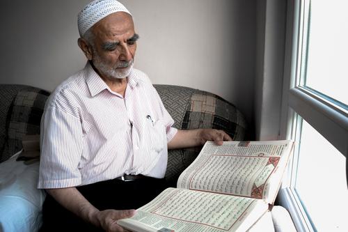 Wise old muslim man wearing taqiyah reads Turkish translation of Quran in passion wise qur'an islam quran koran skullcap window sitting beard religion turkey