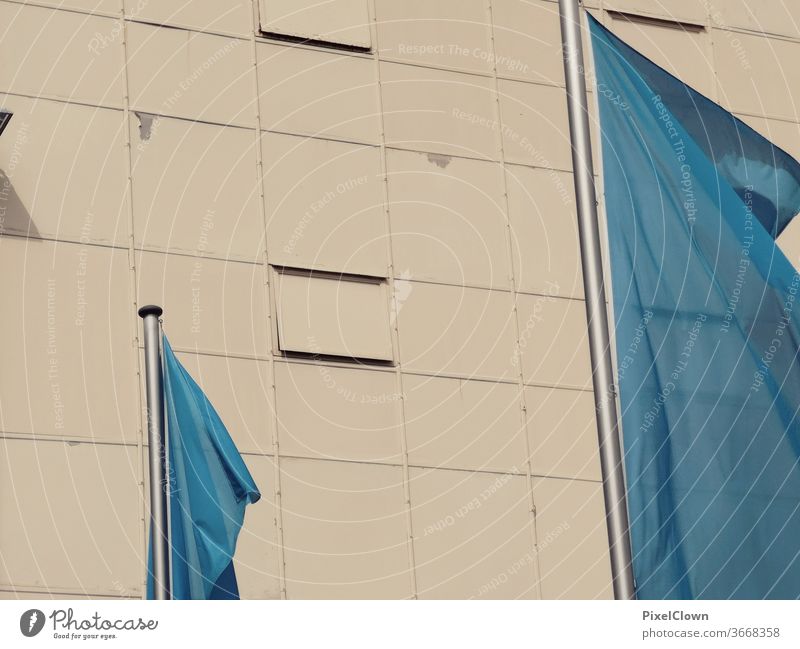 Blue flags in front of a wall Flag Sky Flagpole Wall (barrier) Wall (building) Facade Town Architecture built Deserted