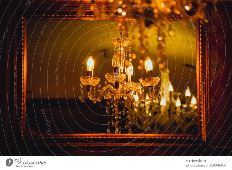 The party is about to start. The candle chandelier is already on and in the mirror with golden frame you can see the lit candles. Mirror Glass Reflection