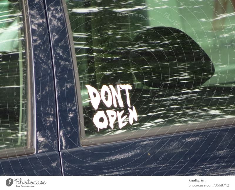 Sticker "DONT OPEN" on the side window of a car door of a black passenger car Communication Car Window Signs and labeling stickers Warn Signage Warning label