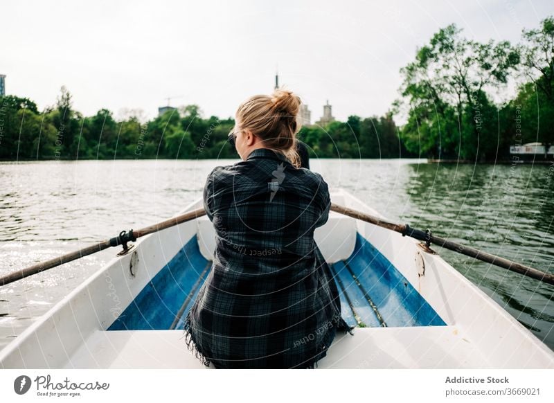 Anonymous woman rowing on boat on lake surface positive sculling oar nature activity peaceful calm relax summer leisure lifestyle female travel beautiful